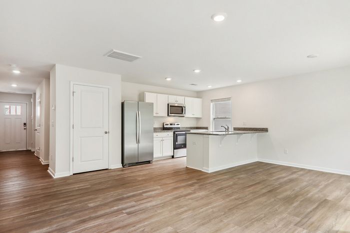 Bright, open-concept kitchen with modern stainless steel appliances, sleek countertops, and elegant wood flooring, perfect for entertaining in style.