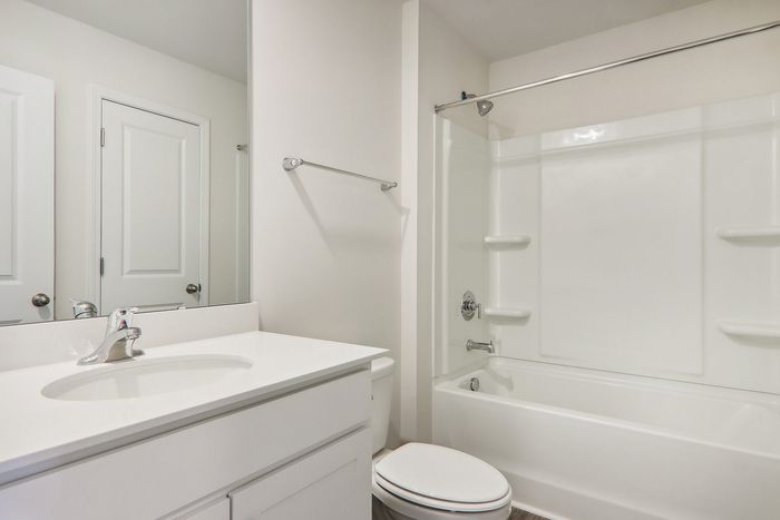 Bright and modern bathroom with sleek white fixtures, a bathtub with shower, and ample counter space.