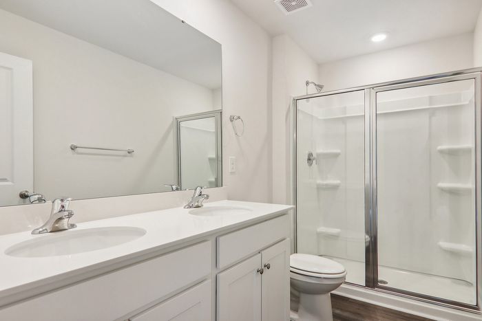 Modern bathroom featuring a sleek double vanity, spacious glass-enclosed shower, and elegant fixtures.