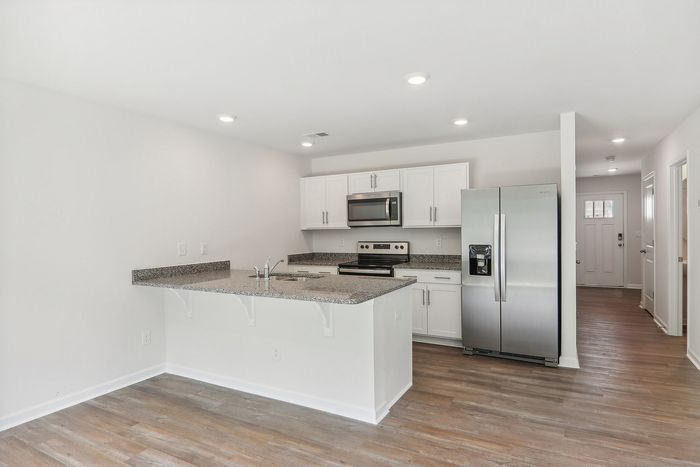 Modern kitchen featuring sleek stainless steel appliances, elegant granite countertops, and bright white cabinetry in a spacious open layout.