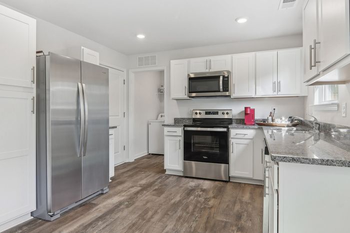Modern kitchen with stainless steel appliances, sleek white cabinets, and elegant granite countertops.