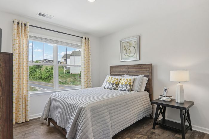 Bright and inviting bedroom with modern decor, featuring a large window letting in natural light, elegant curtains, and a cozy bed with stylish pillows.