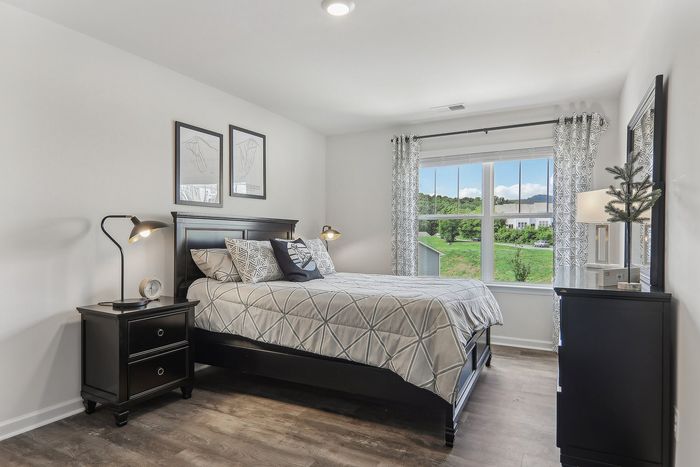 Bright and inviting bedroom with modern decor, large window offering scenic views, and stylish furniture to create a cozy sanctuary.