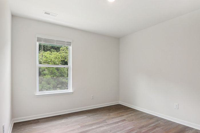 Bright and airy room with large window offering lush green views, perfect for a cozy bedroom or tranquil office space.