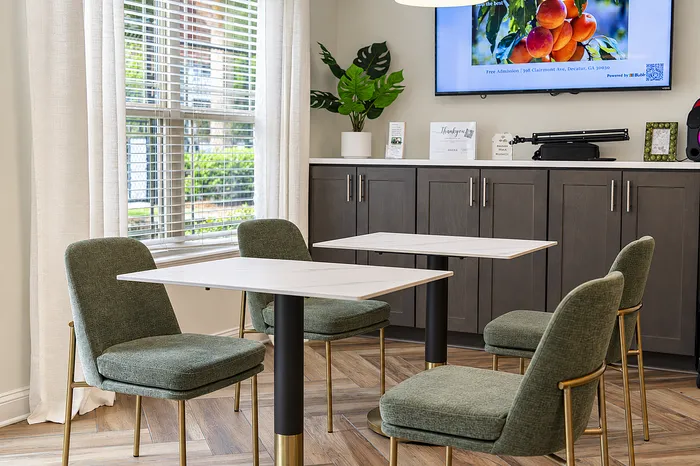 Bright and modern dining area with sleek green chairs and elegant marble tables, perfect for a cozy meal or casual gathering.