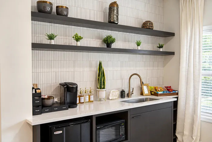 Chic kitchenette with sleek cabinetry, modern sink, and stylish open shelving adorned with plants.