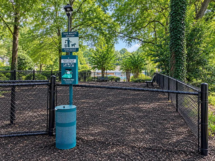 Inviting dog park with tidy waste station and lush greenery, perfect for pet-friendly living.