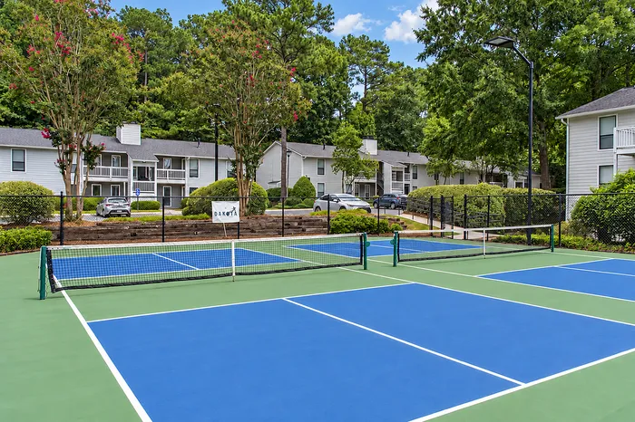 Vibrant community setting with professional tennis courts and scenic greenery, showcasing modern apartment living.