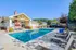 Inviting residential pool area with modern lounge chairs, surrounded by lush greenery and a charming clubhouse in the background.