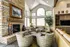 Inviting living room with a cozy stone fireplace, modern armchairs, and expansive windows providing natural light.