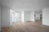Spacious and inviting apartment entrance with light wood flooring, white walls, and ample natural light.