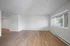 Spacious room with light wood flooring and large window, offering abundant natural light.