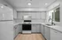 Modern kitchen with sleek white cabinetry, stainless steel appliances, and large window offering natural light.