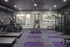 Modern gym with treadmills, stair climbers, weight machines, and purple-accented flooring.