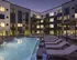 Luxurious pool area at night with lounge chairs, warm apartment lighting, and modern glass fencing.