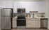 Sleek kitchen with white cabinets, stainless steel appliances, wood accents, and minimalist decor.