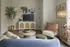 Living area with a blue sofa, wooden coffee table, TV console, bar cart, and decorative plants.