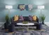 Chic living room with plush black sofa, vibrant pillows, modern art, and elegant decor.