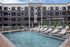 Contemporary apartment complex with a luxurious outdoor pool area featuring stylish lounge chairs and a pergola, perfect for relaxation and leisure.