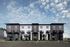 Modern apartment building with stylish balconies and sleek architecture, set against a picturesque blue sky.