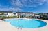 furnished pool and sundeck with townhomes behind it on sunny day