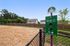outdoor pet park with sign and trash can on sunny day