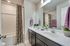 Decorated bathroom with dark wood cabinetry and dual vanity