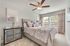Furnished guest bedroom with plush carpet and ceiling fan