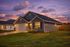 Charming suburban home illuminated at sunset, with a welcoming front porch and lush green lawn.