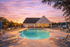 Inviting outdoor pool with surrounding lounge chairs at sunset beside a charming clubhouse, perfect for relaxation and community gatherings.