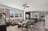Bright and modern open-concept living room with elegant furnishings, large windows providing natural light, and a seamless flow into the contemporary kitchen and dining area.