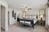 Elegant master bedroom with plush carpeting, stylish decor, and natural light streaming through large windows.