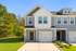 Charming modern home exterior with a two-car garage, sleek grey siding, and inviting front entrance, set against a lush green landscape.