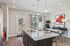 Elegant open kitchen and dining area featuring sleek granite countertops, stylish pendant lighting, and a modern dining setup with vibrant wall art.