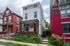 Charming urban home with classic brick accents, nestled between vibrant neighboring houses, featuring a cozy porch and lush greenery, ideal for city living.