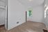 Bright and airy room with sleek hardwood floors, large window for natural light, and modern white walls.