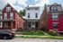 Charming urban apartment with a classic brick facade nestled between vibrant homes on a tree-lined street, offering cozy city living.
