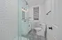 Modern bathroom featuring chic patterned tile flooring, sleek subway tile shower, and contemporary fixtures with bright ambient lighting.