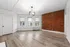 Chic apartment room featuring a stylish exposed brick wall, modern lighting, and large windows for abundant natural light.
