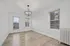 Bright and elegant living space featuring large windows, modern wood floors, and a chic chandelier.