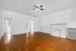 Bright and spacious living room featuring elegant hardwood floors, a stylish ceiling fan, and a classic white fireplace, offering a welcoming ambiance.