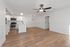 Modern apartment kitchen and living area with sleek white cabinetry, stainless steel appliances, and elegant wood flooring.