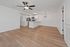 Chic open-concept living area with elegant wood flooring, modern kitchen with stainless steel appliances, and stylish ceiling fan.