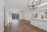 Elegant open-concept living space with hardwood floors, modern chandelier, and sliding glass doors leading to a scenic balcony.
