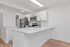 Bright modern kitchen featuring sleek white cabinetry, stainless steel appliances, and a spacious white countertop island.