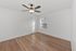 Bright and inviting bedroom with elegant wooden flooring and a modern ceiling fan, offering a serene view through the large window.
