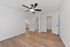 Bright, modern room with hardwood floors and stylish ceiling fan, leading to a sleek bathroom and well-lit hallway.