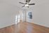 Bright and spacious bedroom with elegant wood flooring, modern ceiling fan, and large closet space, featuring ample natural light through a wide window.