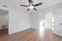 Bright, empty room with elegant wooden flooring and a modern ceiling fan, inviting natural light through an open door.