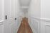Elegant hallway with crisp white walls and luxurious wooden flooring leading to an inviting living space.